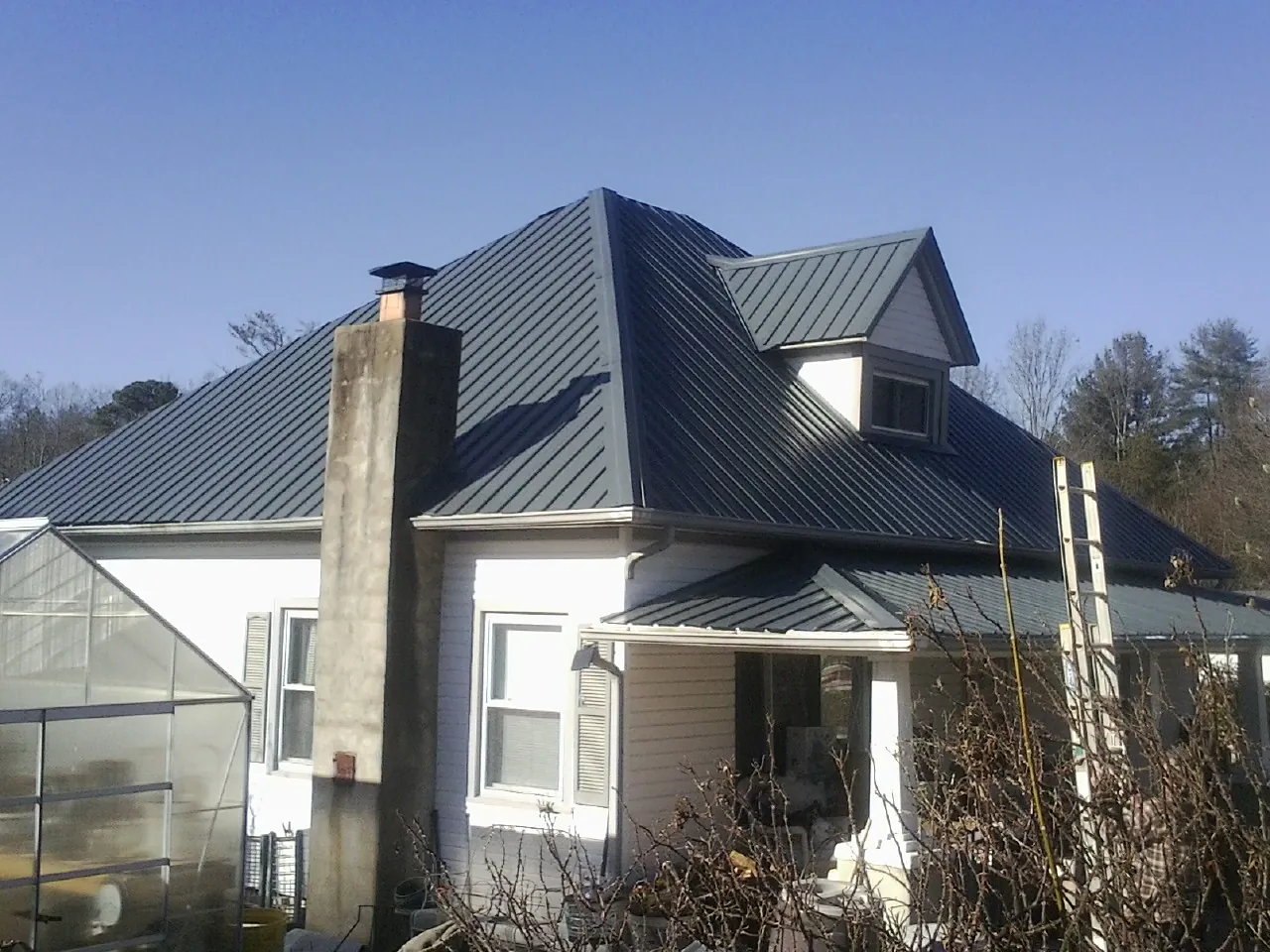 Dark blue standing seam metal roof on a white farmhouse with dormer — Slate & Tile Roof Repair by Roofing Brothers in Haugan