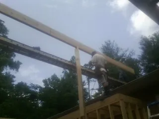 Carpenter setting a ridge beam over a new addition frame — Ice Dam Removal by Roofing Brothers in Haugan