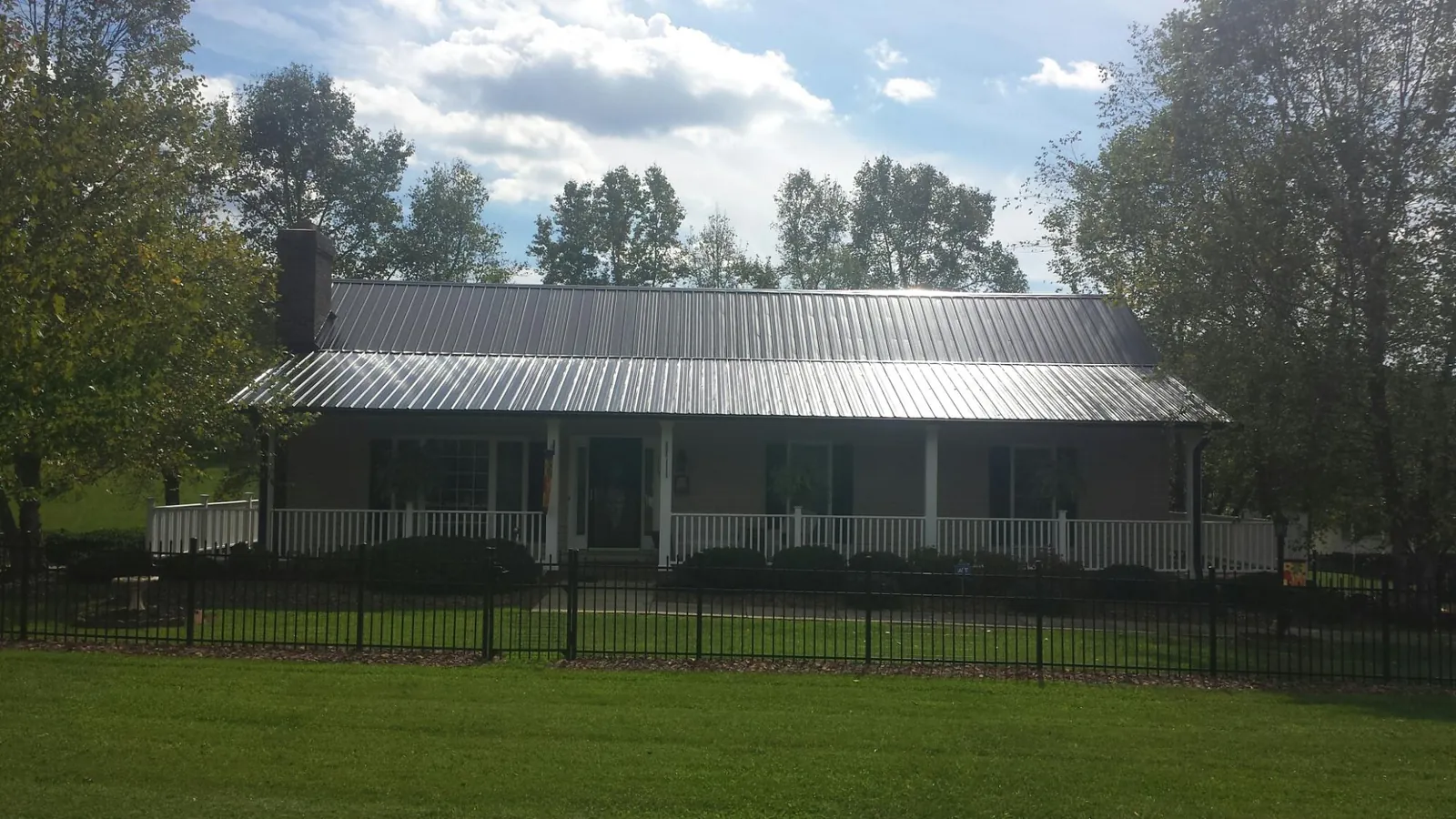 Gray metal roof on a brick ranch with a full width front porch — Gutter Guard Installation work by our crew in Haugan