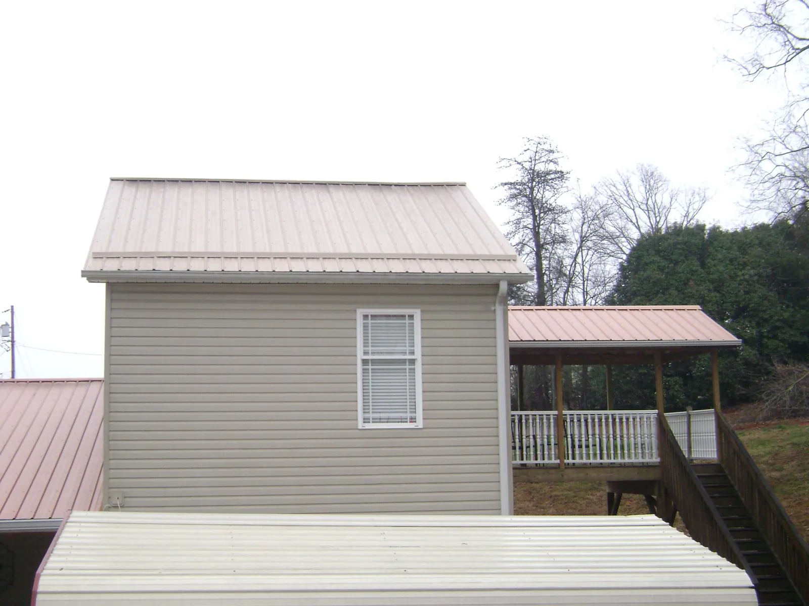 Tan metal roofs on a two story addition and attached porch, from a Roof Replacement job in Haugan